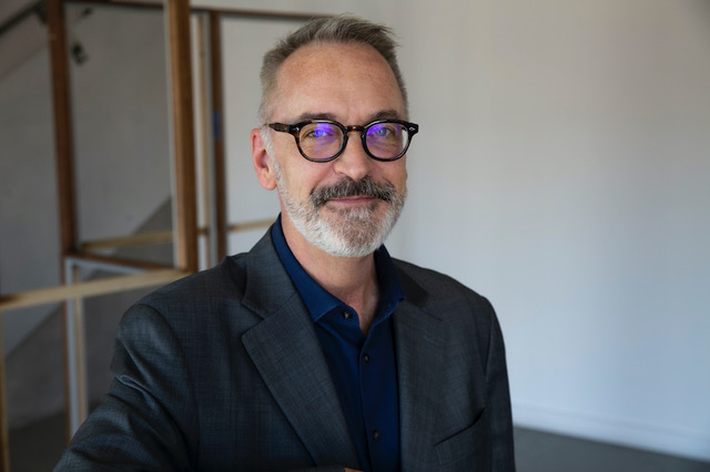 man with salt and pepper hair and beard with dark rimmed glasses