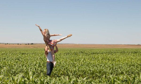 man lifts woman in a corn field
