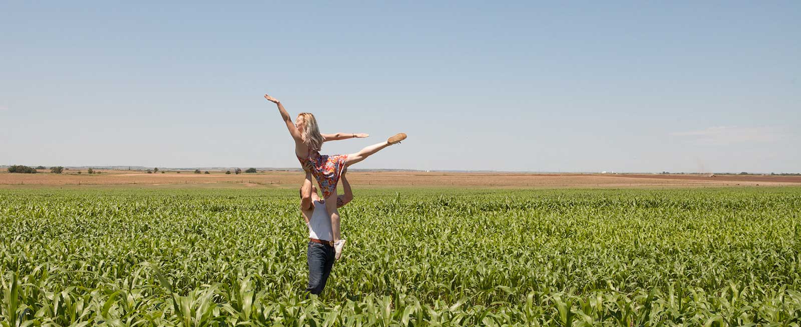 man lifts woman in a corn field