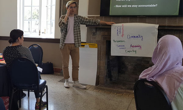 man stands before group of people giving a presentation