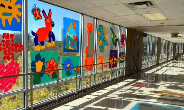 Colorful artwork decorates a long hallway of windows