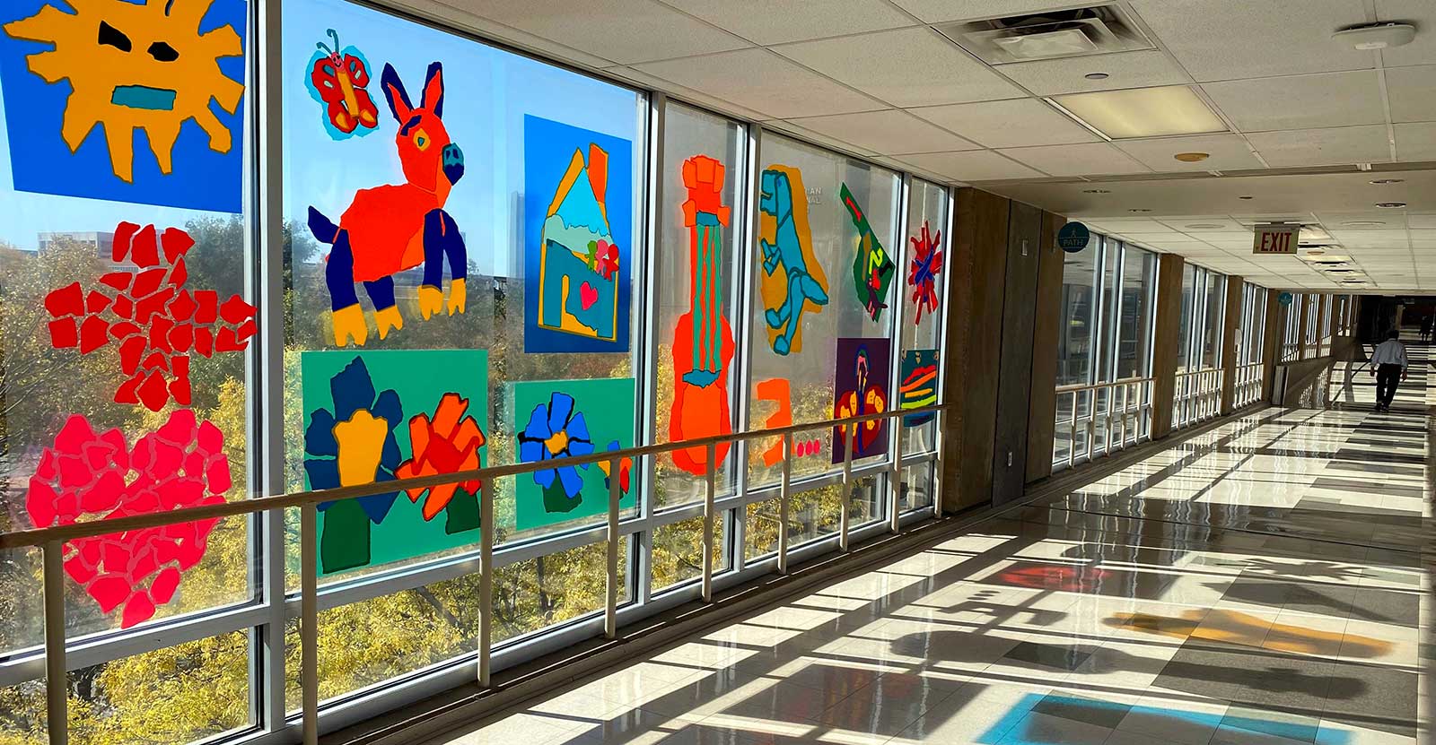 Colorful artwork decorates a long hallway of windows