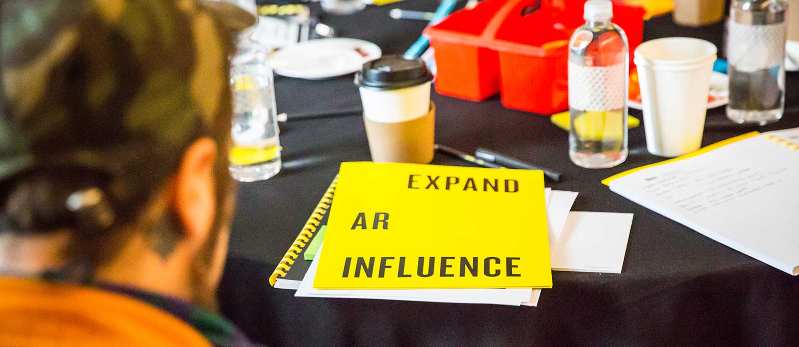 yellow workbook sits on a crowded black table