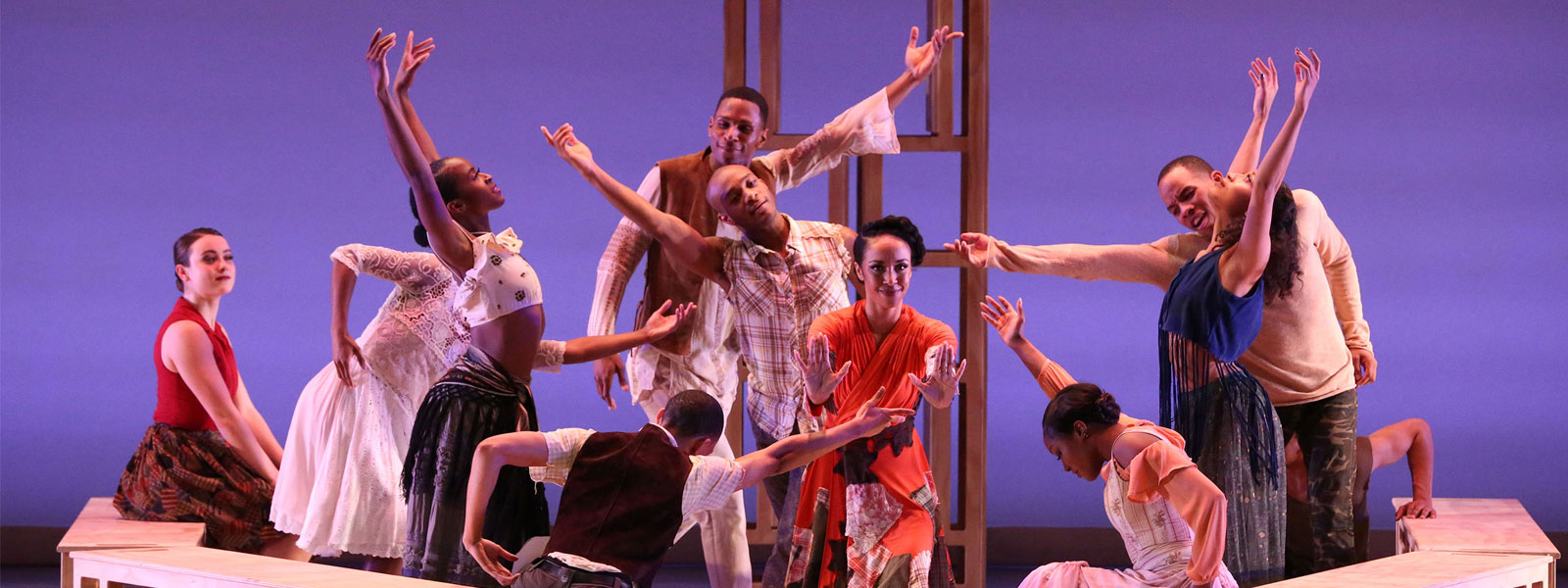 A group of dancers perform against a blue background