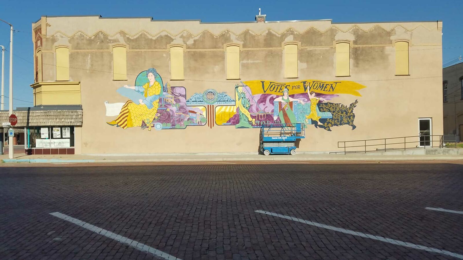 Shot of an old brick building with an in-progress suffrage mural