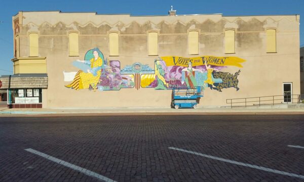 Shot of an old brick building with an in-progress suffrage mural