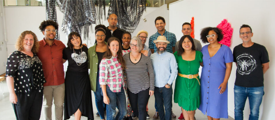 A group of people pose in front of a hanging sculpture