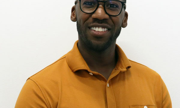 man with dark rimmed glasses and yellow shirt