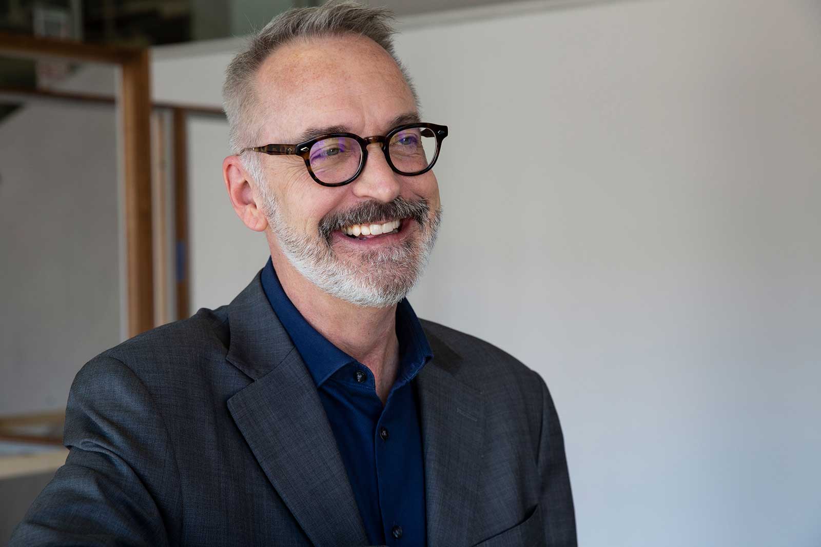 Man with salt and pepper hair and beard with black rim glasses