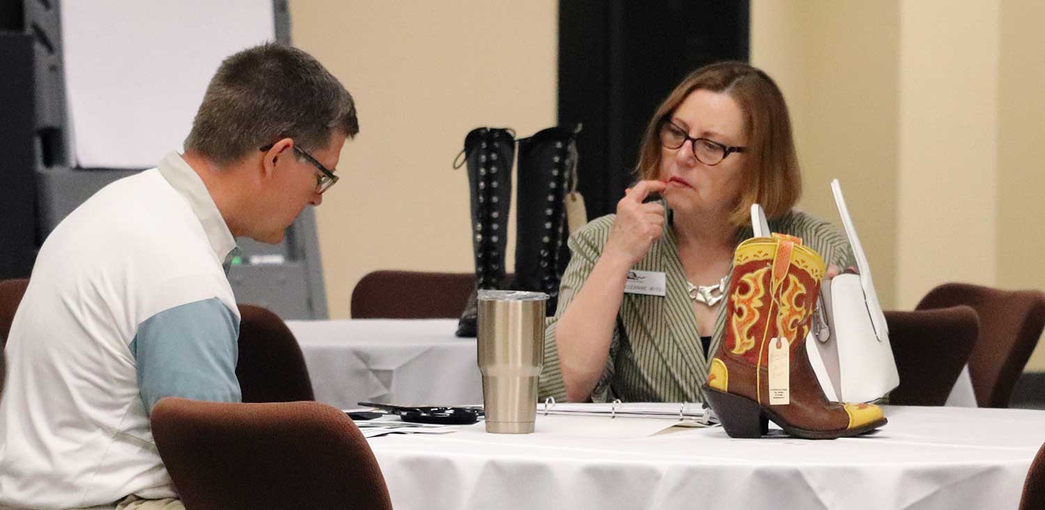 two people in conversation, woman at right has hand pointed to her face as if she's thinking