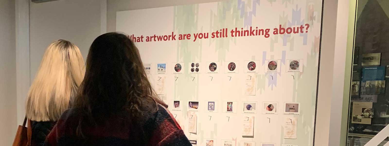 two women look at a wall that says
