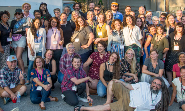 Large group huddle together outdoors for a staff photo.