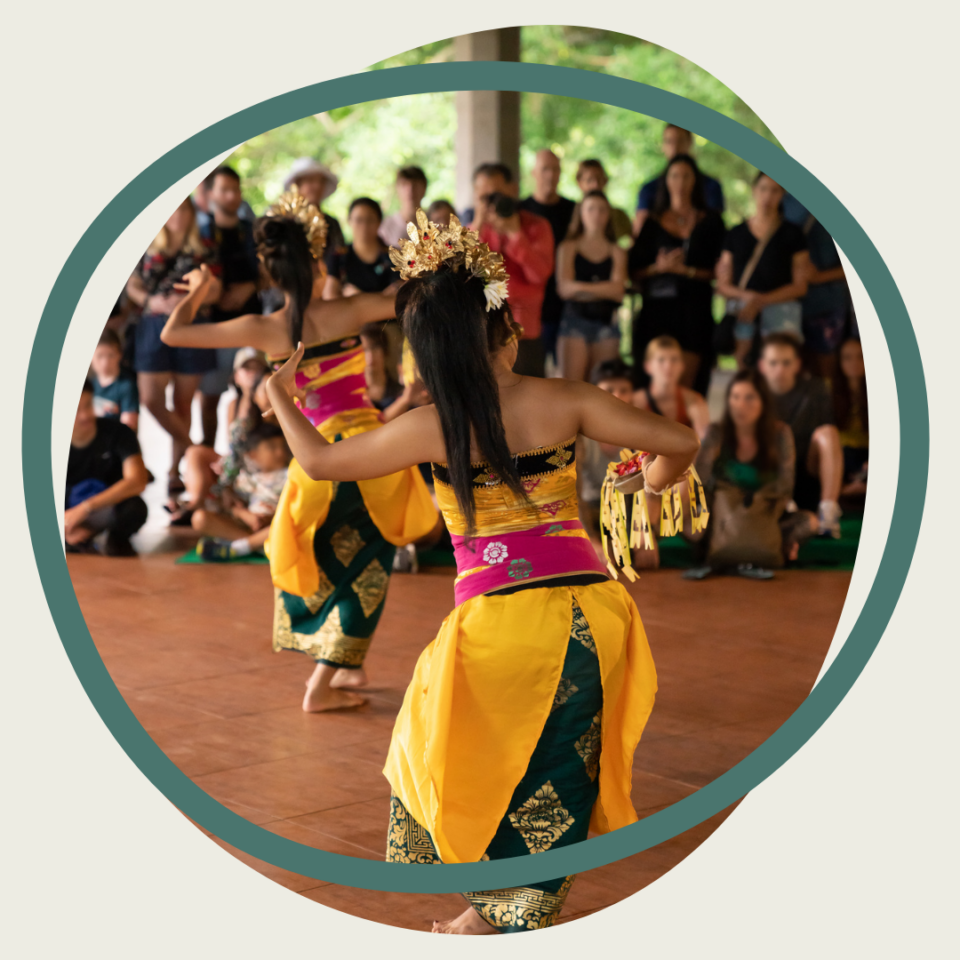 Within a sphere with an overlapping green outline, two Cambodian apsara dancers perform in a tent for a crowd of people.