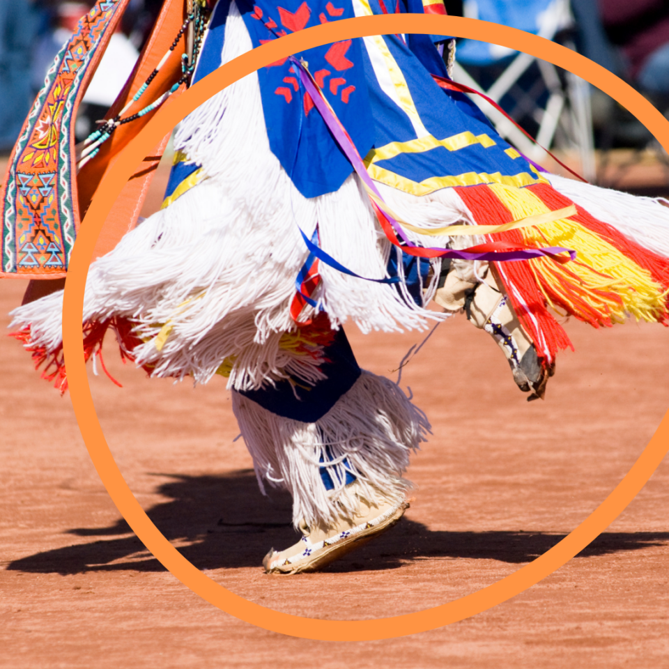 An orange outline of a sphere overlaid on an Indigenous pow-wow dancer’s shoes and dress.