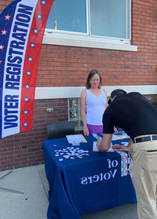 A man in a black shirt signing up to vote at a voter registration table.