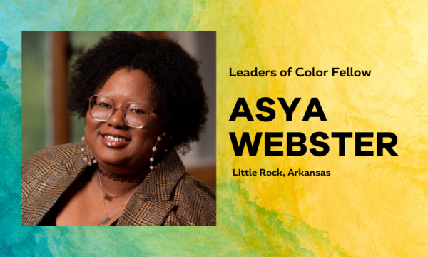 Female-presenting individual with medium dark skin and brown blazer with glasses smiles at camera in a headshot portrait. Background is a colorful blue green yellow painterly gradient with the name Asya Webster written.