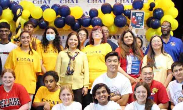 Large group photo with people standing with CHAT t-shirts with balloons behind them.
