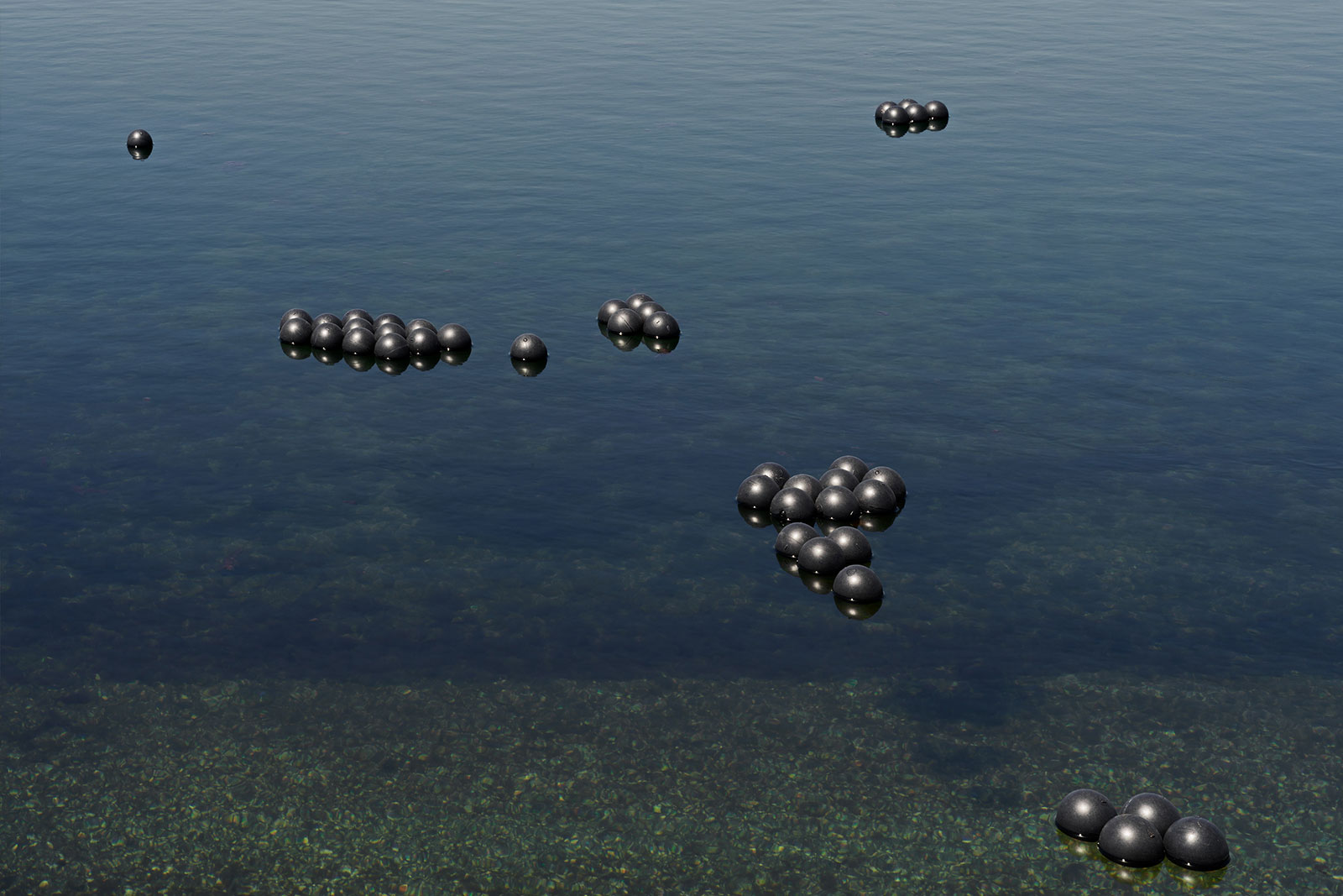 Dozens of black shade balls float in small groupings on the surface of a body of water.