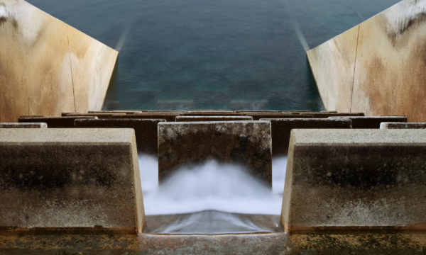 Water flows through concrete diffusers and into a large body of water.