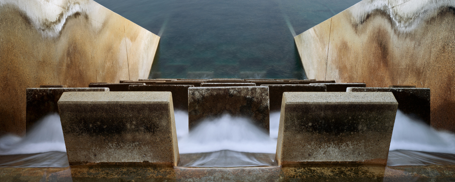 Water flows through concrete diffusers and into a large body of water.