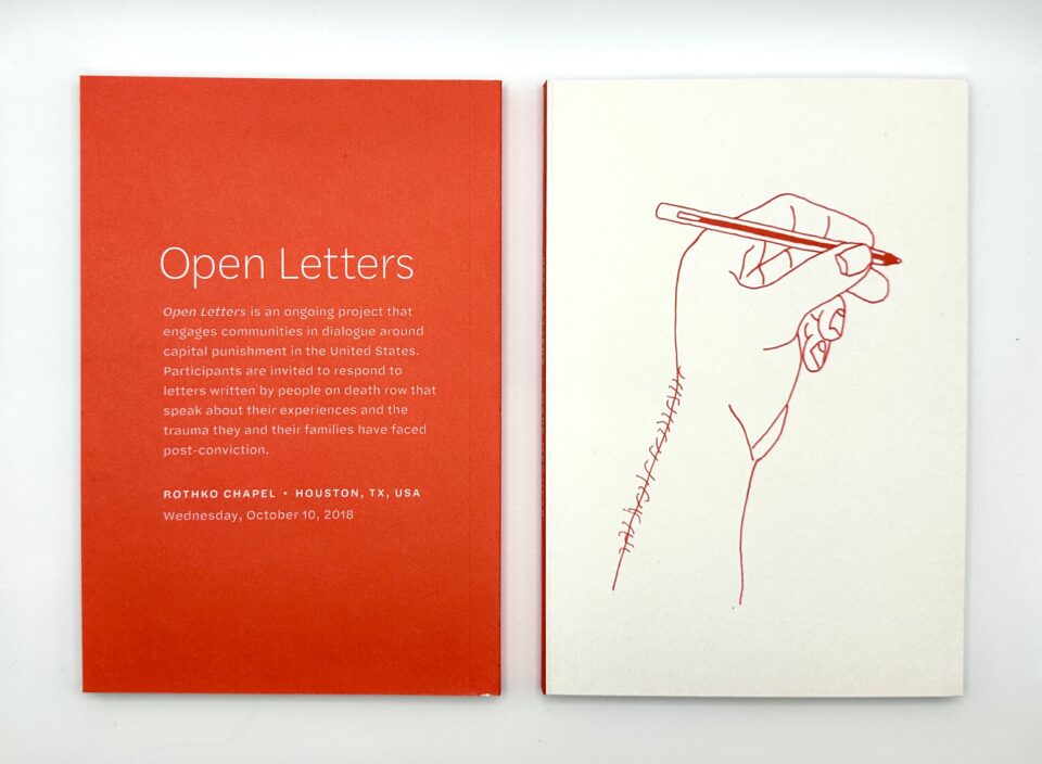 Book that states "Open Letter" on orange paper and a drawing of a hand holding a pencil in red ink.