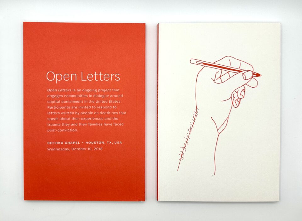 Book that states "Open Letter" on orange paper and a drawing of a hand holding a pencil in red ink.