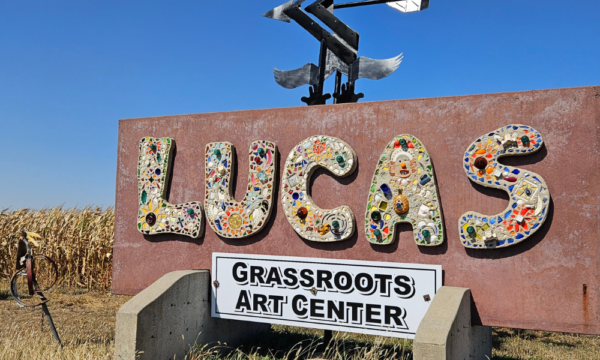 Large outdoor sign that says Lucas with a tall cornfield behind it.