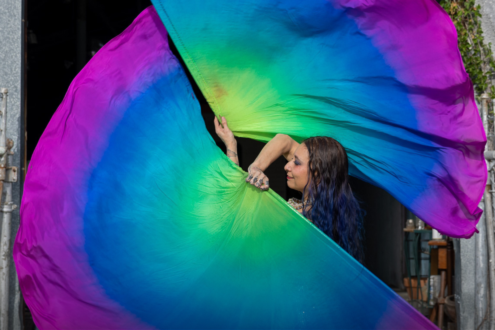 Woman swings large purple blue and green fabric in a circle.