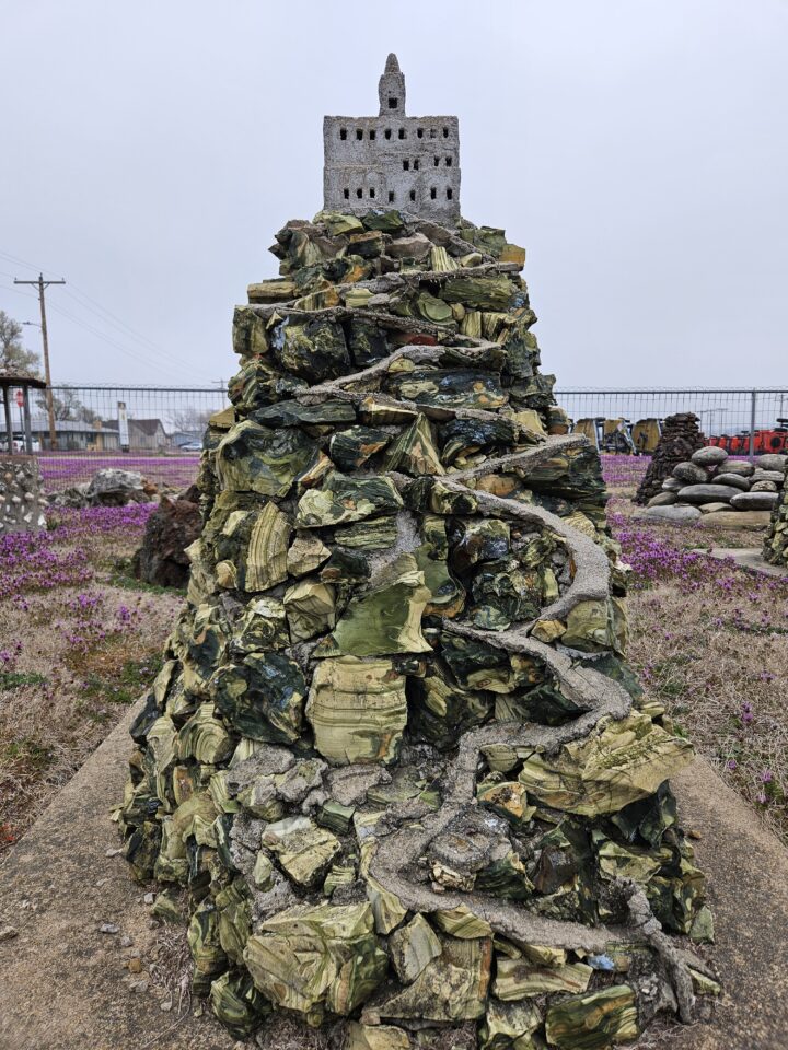 A sculpture of a mountain with a small building on top outdoors.