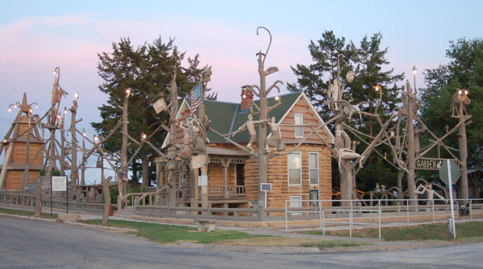 A full size cabin with tall tree-like sculptures surrounding it